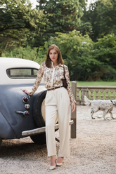 a lady wears a floral printed shirt with white pants
